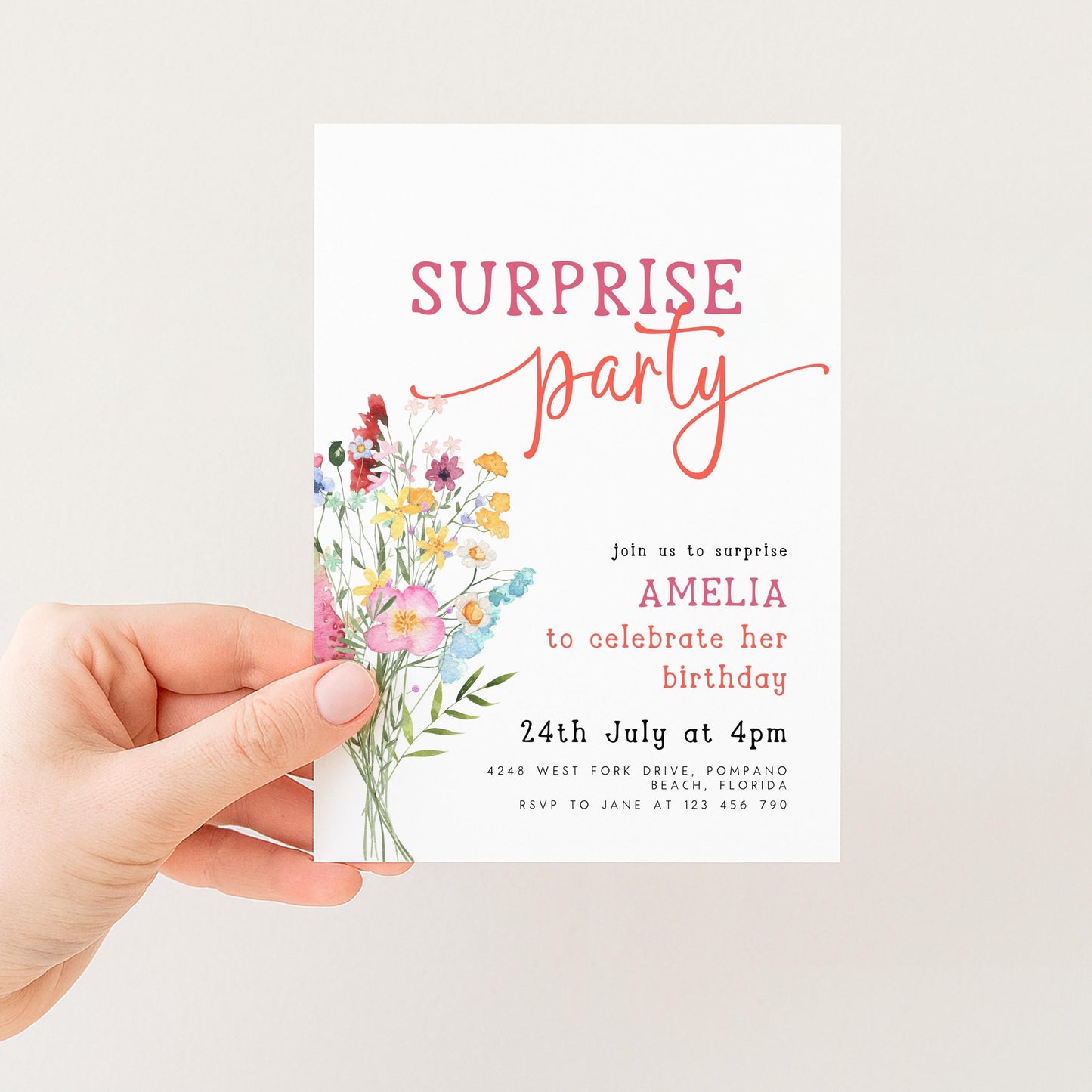 a person holding a white invitation card with a floral design and text.