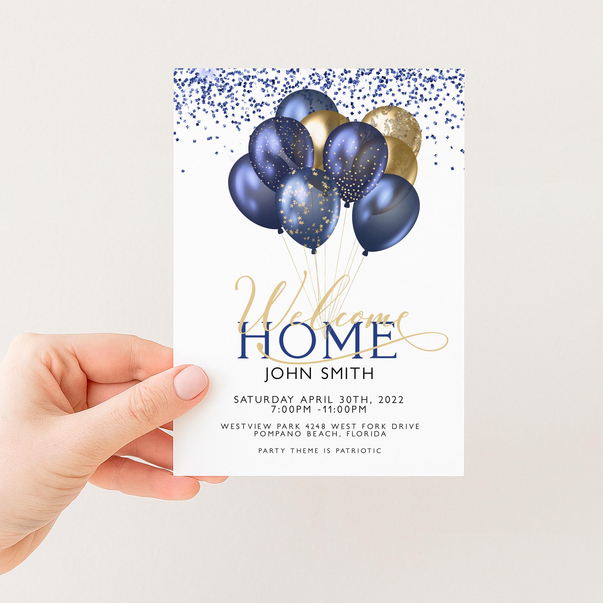 A hand holding a white card with a welcome message and a graphic of blue and gold balloons.