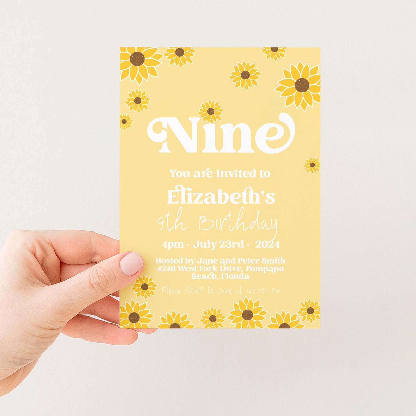 a person holding a yellow birthday invitation card with a yellow floral design.