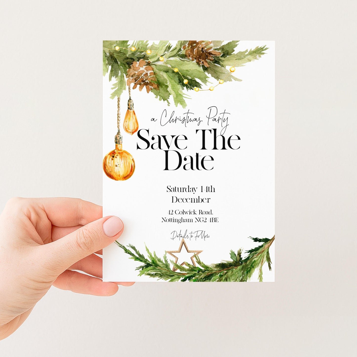 A hand holding a white card with a Christmas-themed design, including a pine tree, ornaments, and greenery.