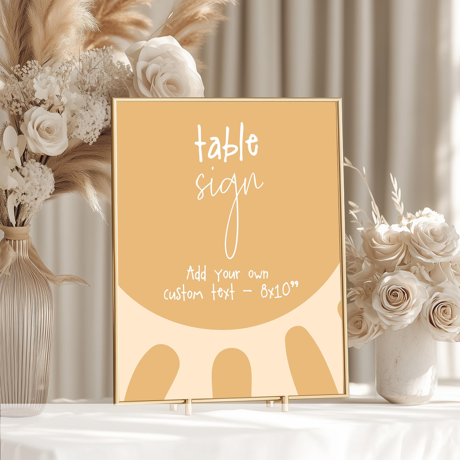 a table sign with a floral design, placed on a table next to a vase of white flowers.