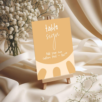 a table sign with a vase of white flowers in the background.