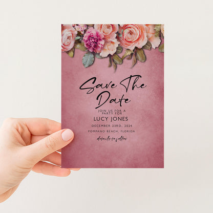 A person is holding a pink wedding invitation card with a floral design and text.