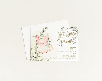 The image is a baby shower invitation featuring a pink and green floral design with a baby's image and text inviting guests to a sprinkler party in honor of Lucy.