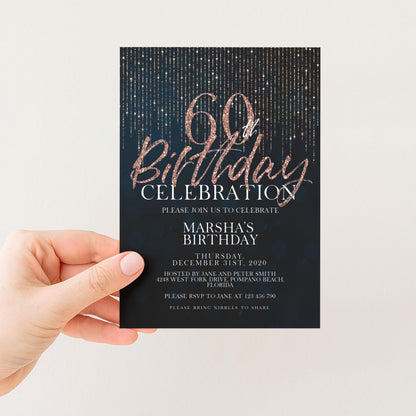 a hand holding a birthday party invitation card with a dark blue background and gold glittering text.