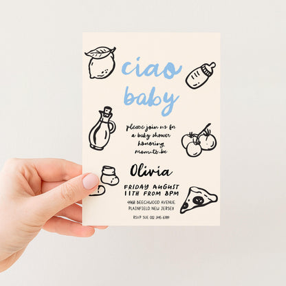 The image is a hand holding a baby shower invitation card with various baby-related illustrations and text.