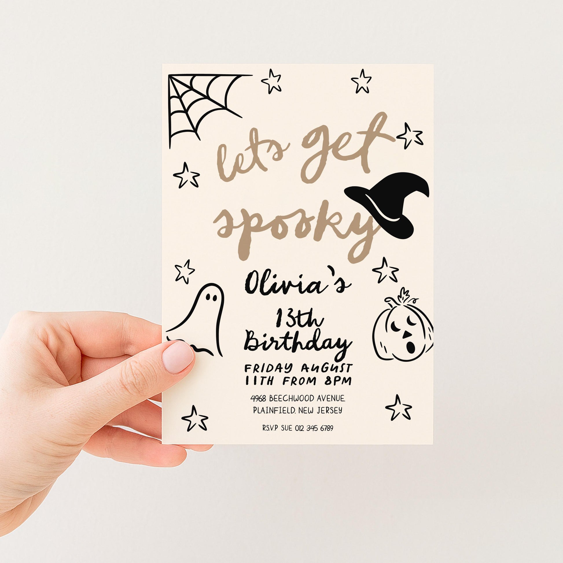 A hand holding a Halloween-themed birthday party invitation card.