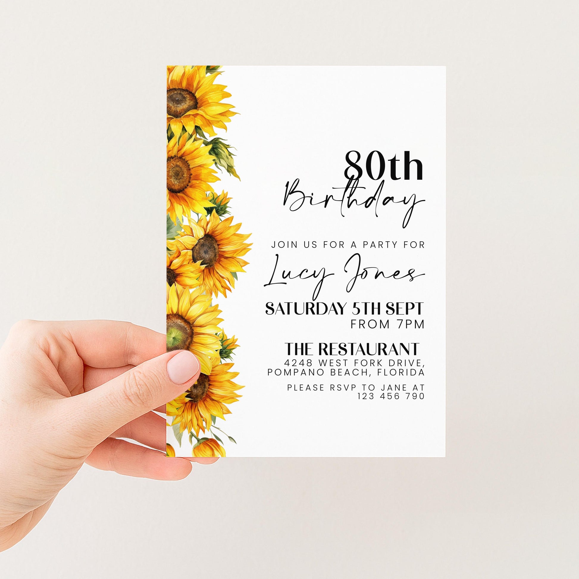 a hand holding a birthday invitation card with a floral design featuring yellow sunflowers.