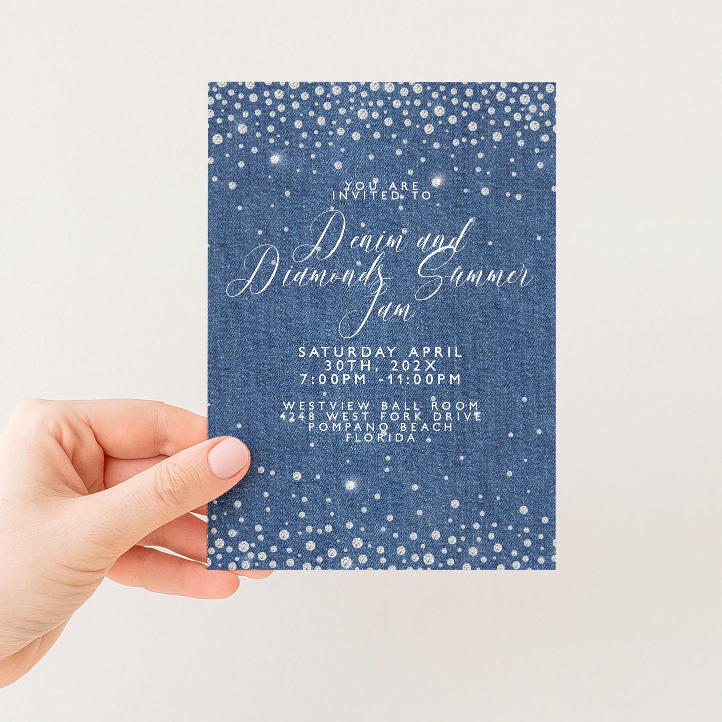a hand holding a blue invitation card with white text and a starry blue background.