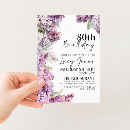 a person holding a birthday invitation card with a floral design.