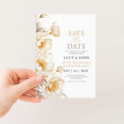 A hand holding a white wedding invitation card with a floral design.
