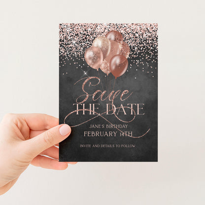A person's hand holding a black and pink birthday invitation card with the text "Save the Date" and "Jane's Birthday February 14th" printed on it.