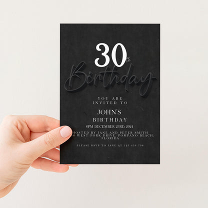 a person holding a black birthday invitation card with white text.