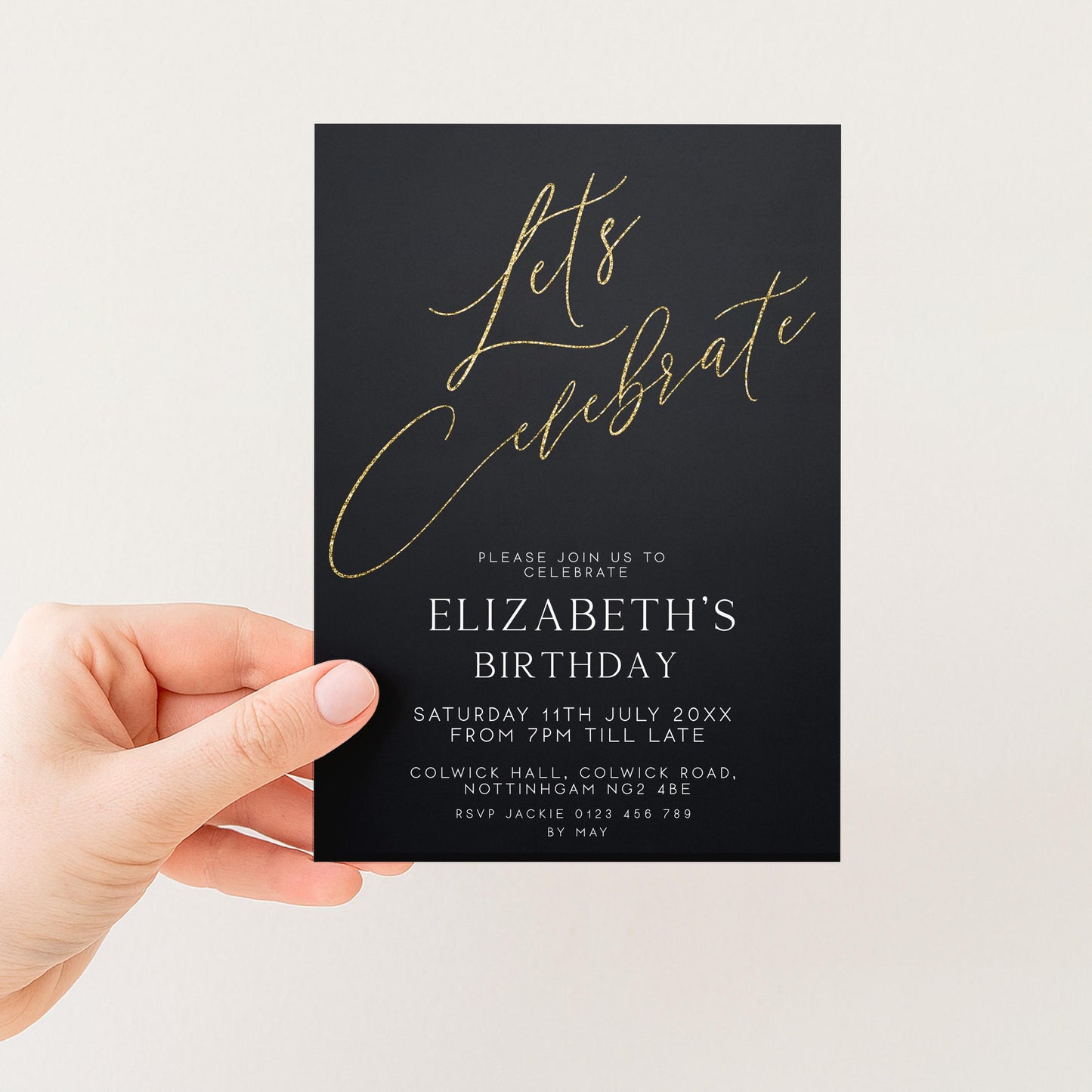 a person's hand holding a black invitation card with gold text and details about an upcoming birthday celebration.