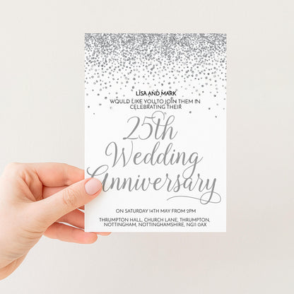 A hand holding a wedding anniversary invitation card with a silver glitter design and text.