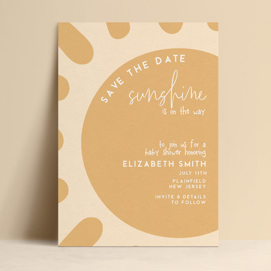 The image is a baby shower invitation featuring a sun-shaped design with a warm, inviting color palette.