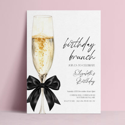 The image is a birthday invitation for Elizabeth's birthday celebration. It features a champagne glass with a black ribbon, and the text invites guests to join the celebration on Saturday, 11th December at 8pm.