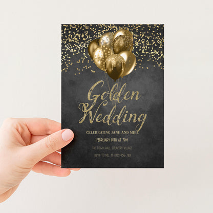 A hand holding a black and gold wedding invitation card with gold foil balloons and confetti on a black background.