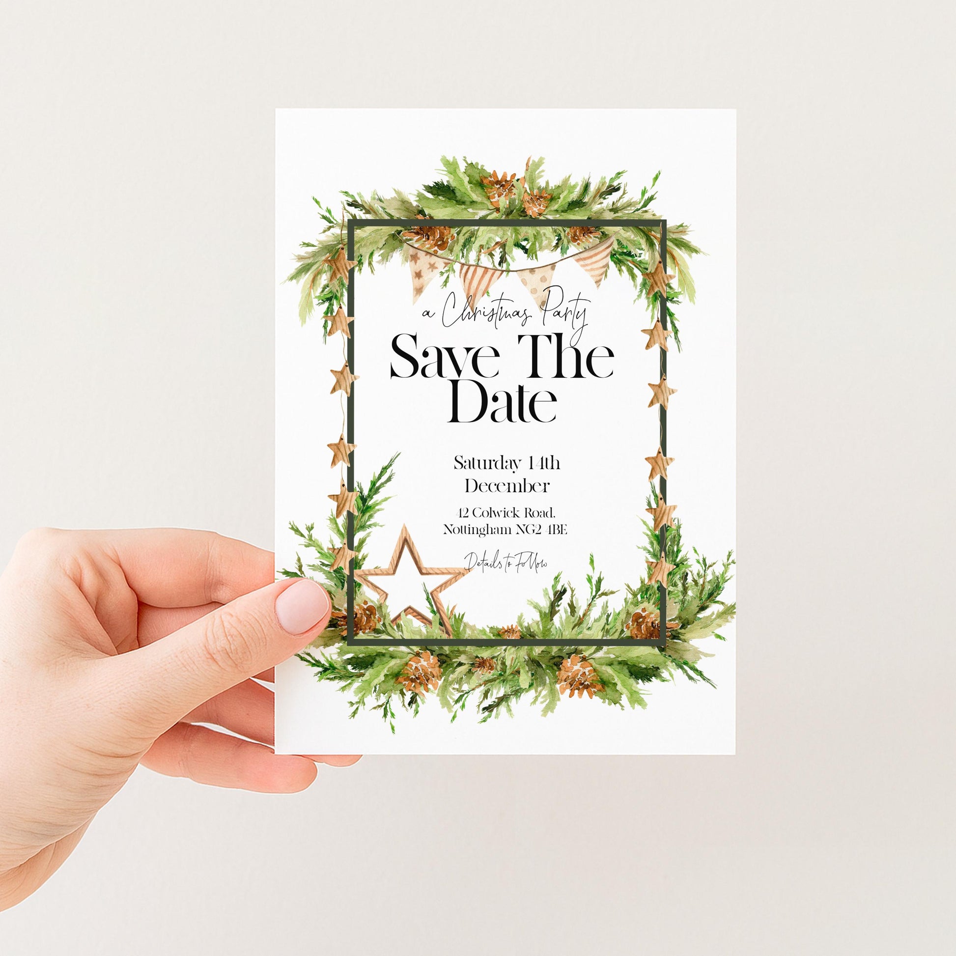 A hand holding a white card with a Christmas-themed design, featuring a wreath and a star.