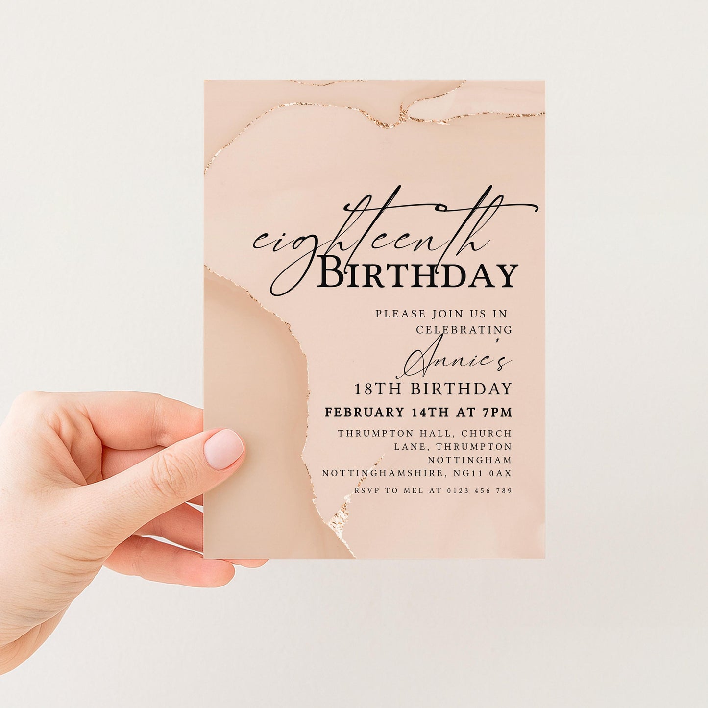 a hand holding a birthday invitation card with a peach-colored background and text.