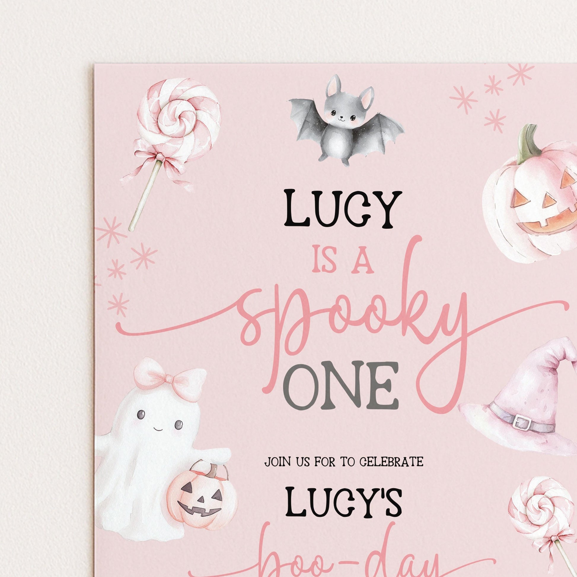The image is a Halloween-themed invitation card with illustrations of a ghost, a witch's hat, a bat, a pumpkin, and a lollipop. The text on the card reads "LUCY is a spooky one" and invites guests to "JOIN US FOR TO CELEBRATE LUCY'S HOO-DAY".