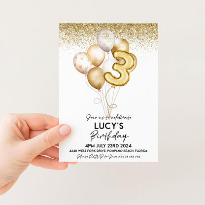 a person holding a birthday invitation card with a gold glitter design and balloons.