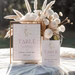 Pink gingham goose table signs in gold frames, styled with neutral florals on a soft table setting, available in 8x10 and 5x7 sizes.
