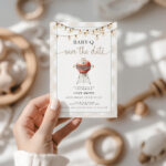 Baby-Q Save the Date invitation card held in hand with wooden toys background