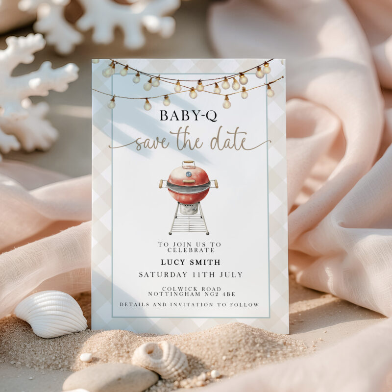 Baby-Q Save the Date invitation in sand with shells and pink fabric background